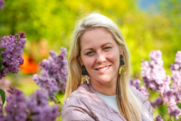 Closeup portrait of a smiling blonde woman in a blossoming garden in spring selective focus