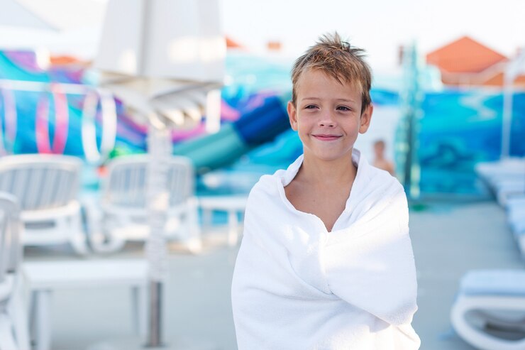 Closeup portrait of a smiling boy wrapped in a towel after swimming in the outdoor pool