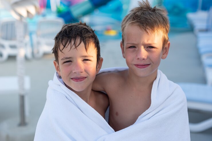 Closeup portrait of a smiling boy wrapped in a towel after swimming in the outdoor pool