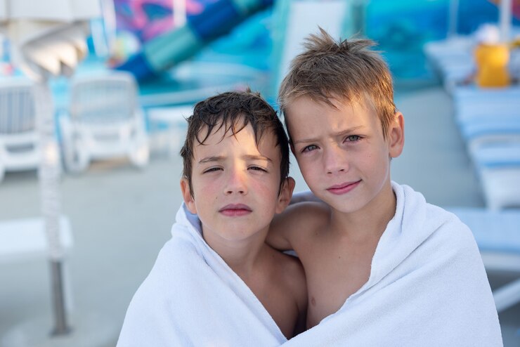 Closeup portrait of a smiling boy wrapped in a towel after swimming in the outdoor pool