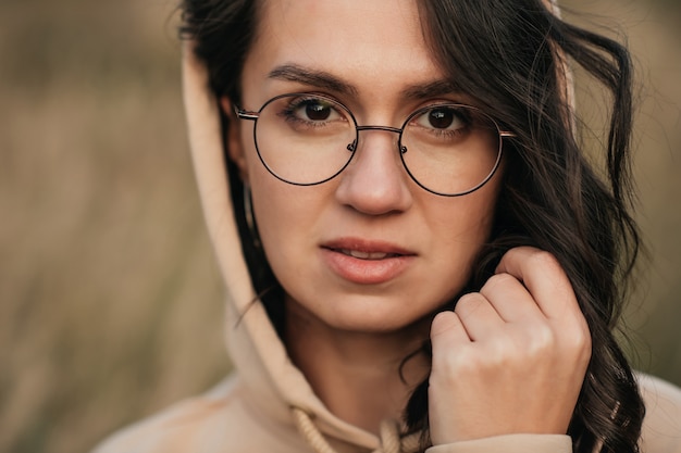 closeup portrait of smiling brunette girl in glasses and hood