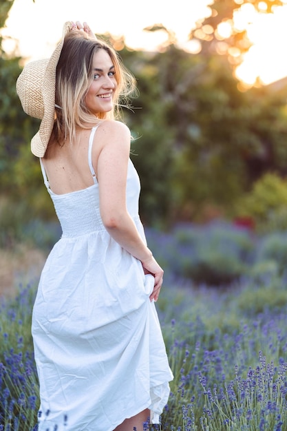 Closeup Portrait of Smiling Girl Standing with her Back Hand Near her Hat on Lavender Meadow