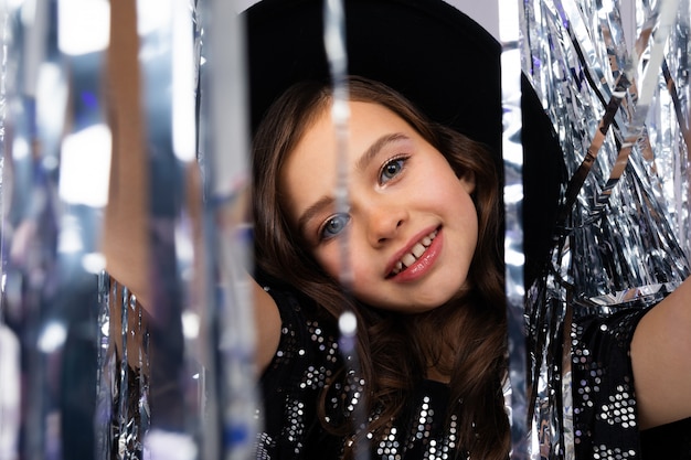 Closeup portrait of smiling glamorous teenage girl in black hat with brim on holiday