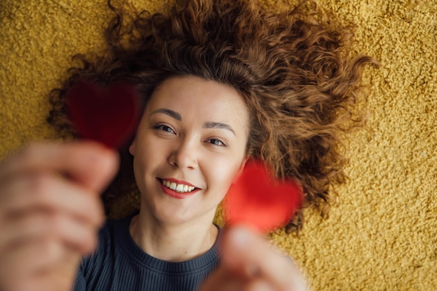 Photo closeup portrait of a smiling woman holding two hearts