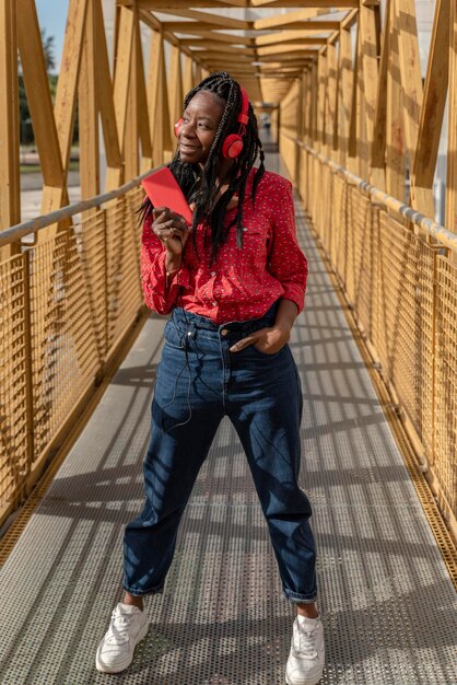 Closeup portrait of a smiling young african american woman with braids listening to music on a yellow bridge