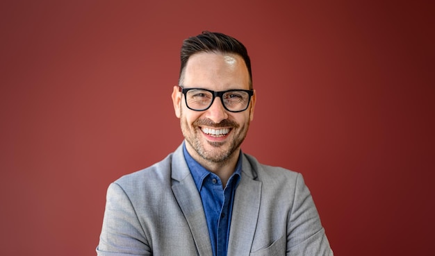 closeup portrait of smiling young businessman in eyeglasses posing against isolated red background
