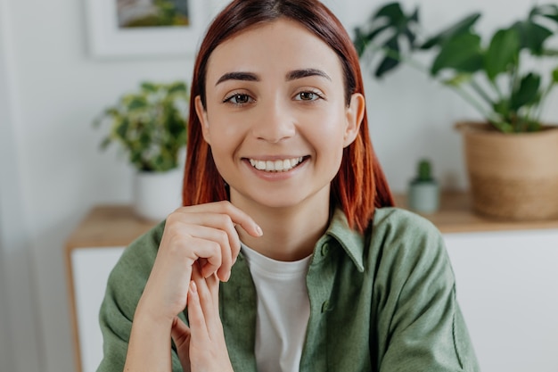 Closeup portrait of smiling young redhead woman at home Concept of lifestyle positive mood