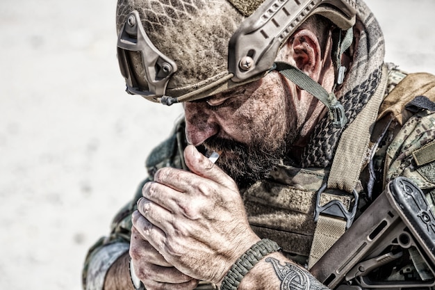 Closeup portrait of smoking soldier in the desert among rocks