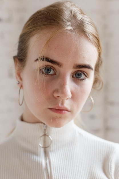 Closeup portrait of thoughtful teen model with blue eyes wearing white sweater