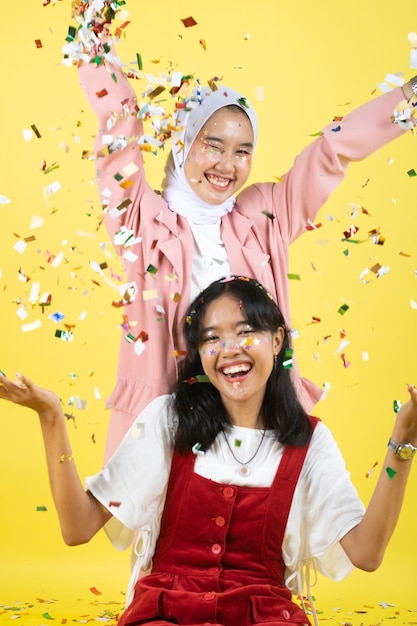 Closeup portrait of two young beautiful  asian woman isolated on yellow background.