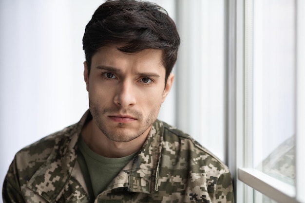 Closeup portrait of upset soldier standing by window