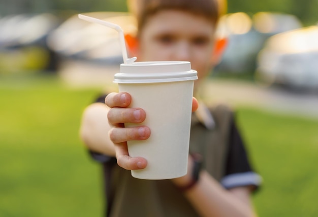 コーヒーの使い捨てカップを持っている子供の手でポートレート、クローズ アップ