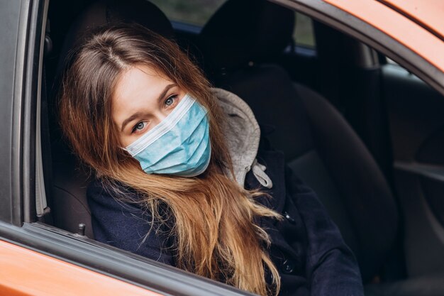 Closeup portrait of a woman in a medical mask in a car. coronavirus epidemic. SARS-CoV-2. Stop COVID-19.