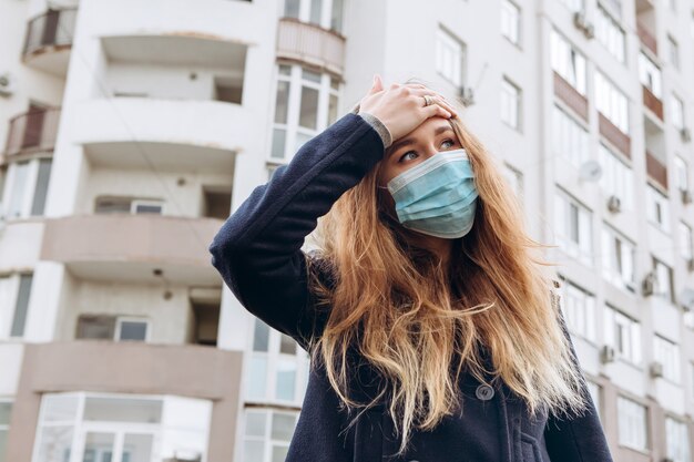 Foto ritratto del primo piano di una donna in una mascherina medica sulla via, epidemia di un coronavirus. la donna ha violato le regole di autoisolamento. sars-cov-2. proteggiti da covid-19.