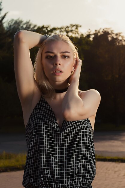 Photo closeup portrait of wonderful blonde woman wearing chocker and sarafan, posing in the city at the evening