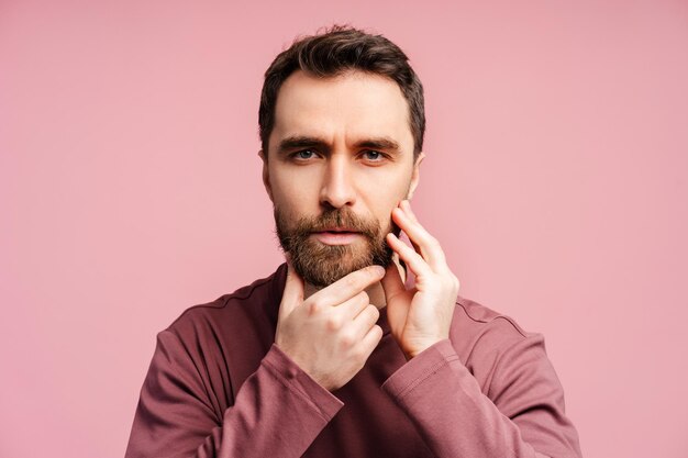 Closeup portrait of worried bearded man looking in mirror and touching beard isolated