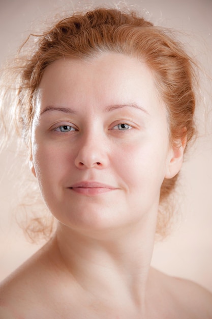 Closeup portrait of a young adult attractive woman with red hair without makeup. Art toning. Soft focus. Neutral background.