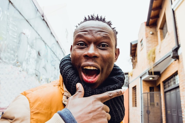 Крупным планом портрет молодого африканца на улице с широкой улыбкой, смотрящего в камеру