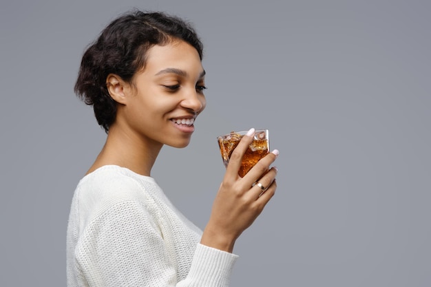 Closeup portrait of young africanamerican woman with a glass of cola with ice in hand