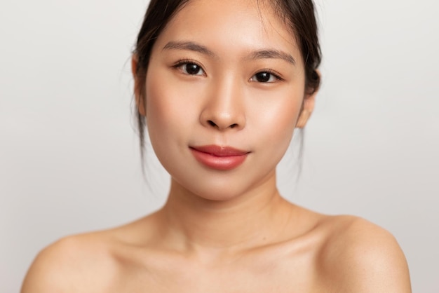 Closeup portrait of young asian lady posing on white studio background looking at camera