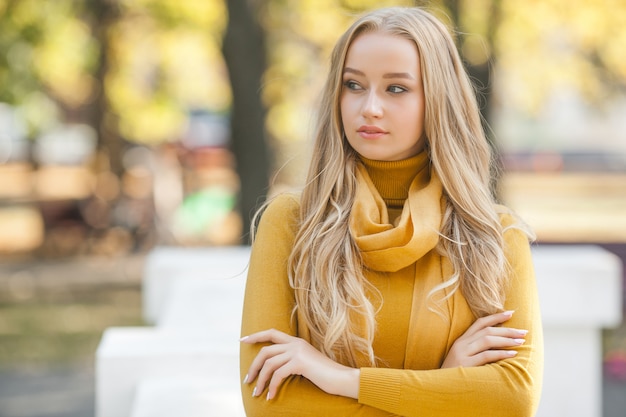Closeup portrait of young attractive woman outdoors with copy space. Beautiful blond girl model. Cheerful ladyin spring, fall, autumn.