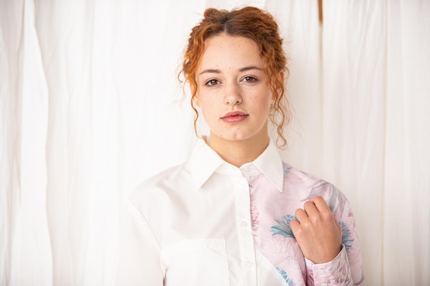 Closeup portrait of young beautiful redhaired woman. Redhead female indoors. Beauty portrait of attractive lady on white background with free space. soft focus