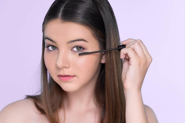 Closeup portrait of young charming applying makeup eyeshadow with brush