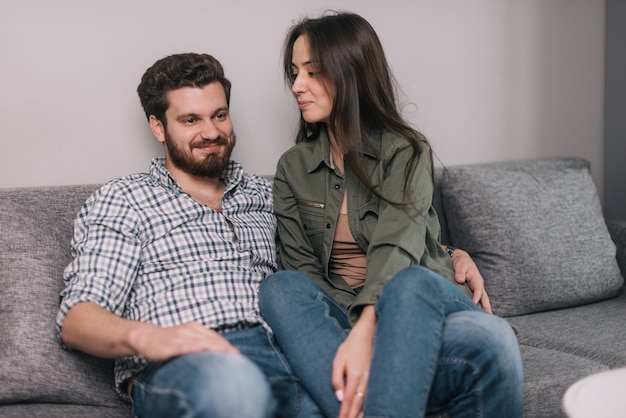 Closeup portrait of young handsome couple is sitting on soft gray couch