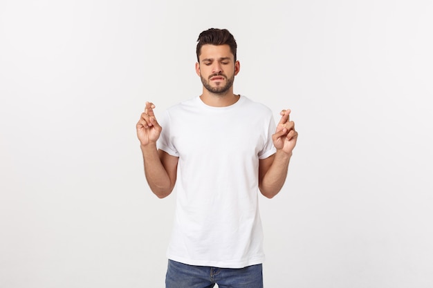 Closeup portrait of young handsome man crossing fingers, wishing, praying for miracle