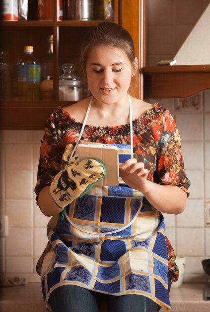 Closeup portrait of young housewife using tablet while cooking