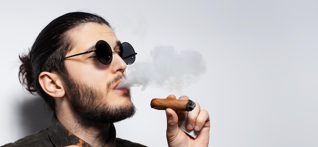 Closeup portrait of young man with a cigar on white background