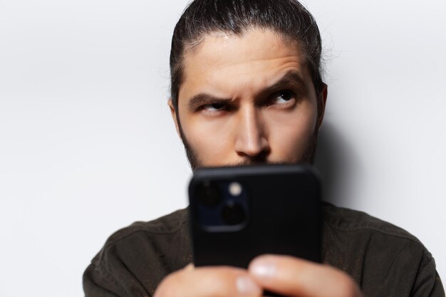 Closeup portrait of young man with smartphone in hands looking up on white