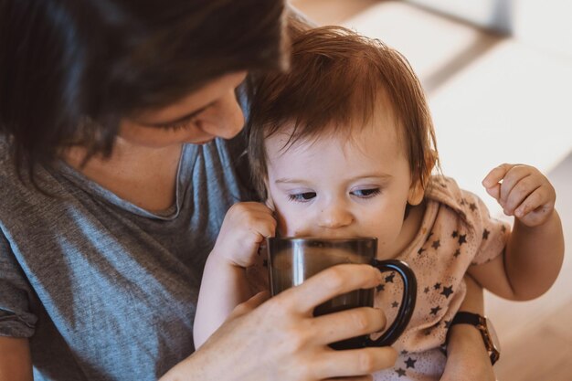 Closeup portrait of young mother and baby daughter having healthy breakfast in the kitchen beautiful