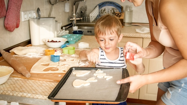 Closeup portrait of young mother teaching her toddler son making cookies