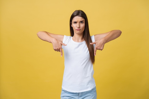 Photo closeup portrait of young pretty unhappy serious woman pointing at someone as if to say you did something wrong bad mistake isolated on yellow background negative emotion facial expression feeling