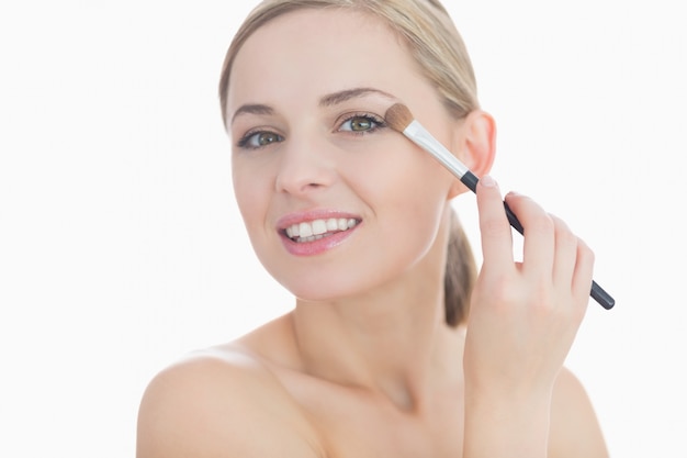 Closeup portrait of young woman applying eye shadow