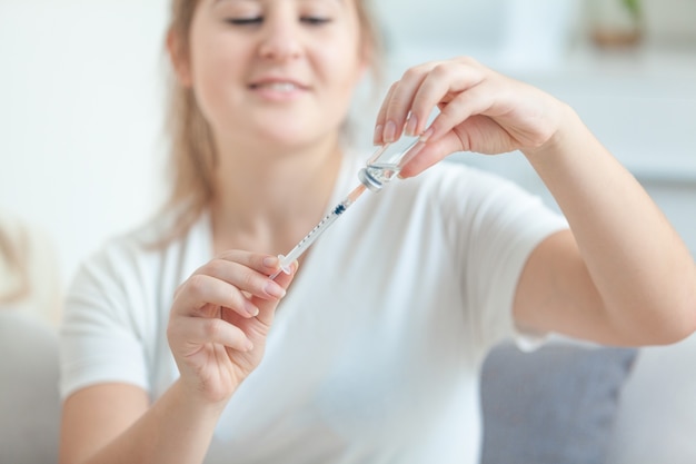 Closeup portrait of young woman filling syringe from ampule