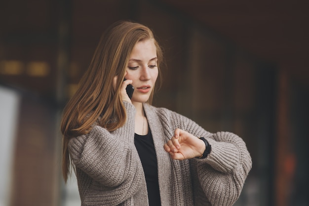 写真 クローズアップの肖像画、携帯電話で話している灰色のビジネススーツブレザーの若い女性が時計の時間切れを心配して、