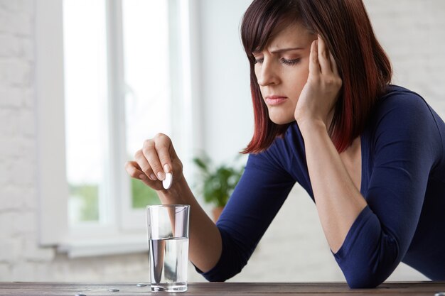 Closeup portrait of young woman suffering from toothache, holding fingers to jaw and closing eyes from pain. 