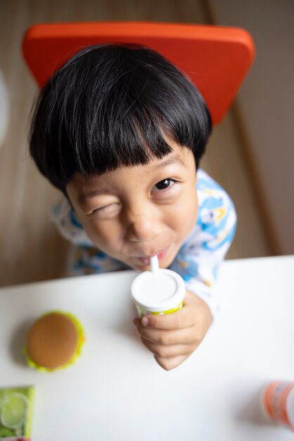 Closeup portret Aziatische kind jongen recht zwart haar draagt een witte pyjama met camera kijken