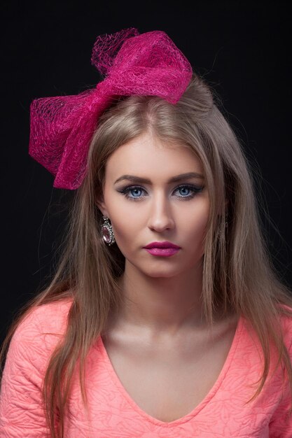 Closeup portret geïsoleerd Blonde model met roze boog