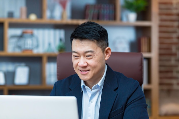 Closeup portret van Aziatische zakenman man glimlachend en kijken naar laptop scherm