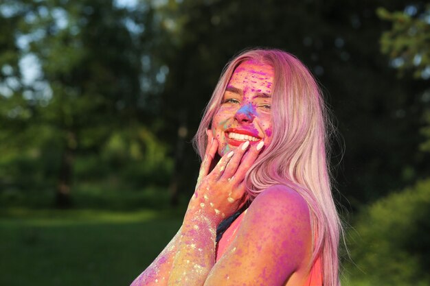 Closeup portret van cool model poseren bedekt met een kleurrijke droge verf in het park