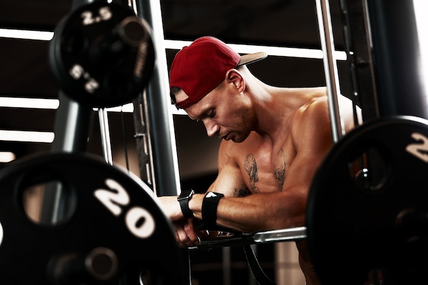 Closeup portret van een gespierde man training met barbell op sportschool. Brutale bodybuilder atletische man met sixpack, perfecte buikspieren, schouders, biceps, triceps en borst.