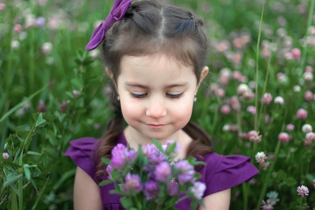 Closeup portret van een klein meisje met grote mooie ogen en met een boeket van wilde bloemen