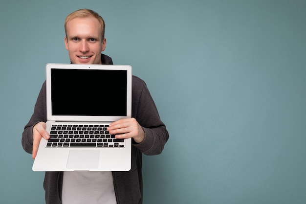 Closeup portret van knappe lachende blonde man met computer laptop met leeg beeldscherm