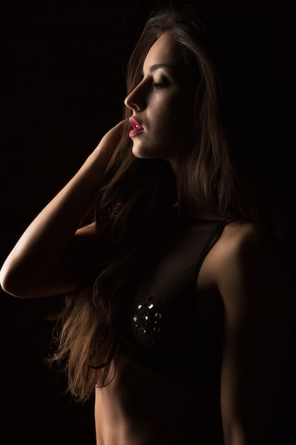 Closeup portret van mooie jonge vrouw met weelderig haar in zwarte lingerie poseren in de schaduw
