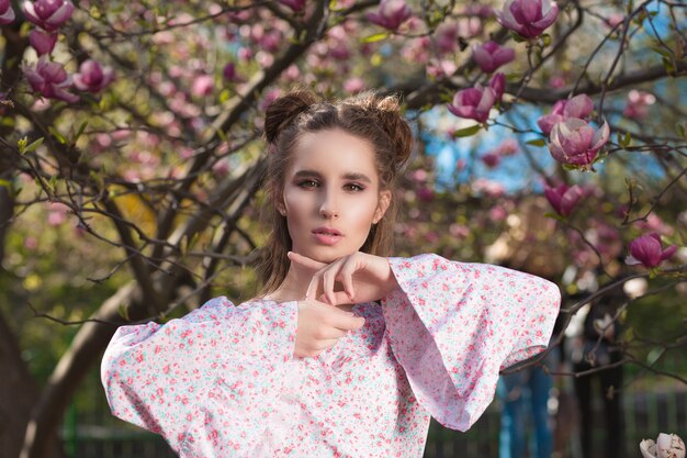 Closeup portret van prachtige brunette model staande in bloeiende magnoliatuin