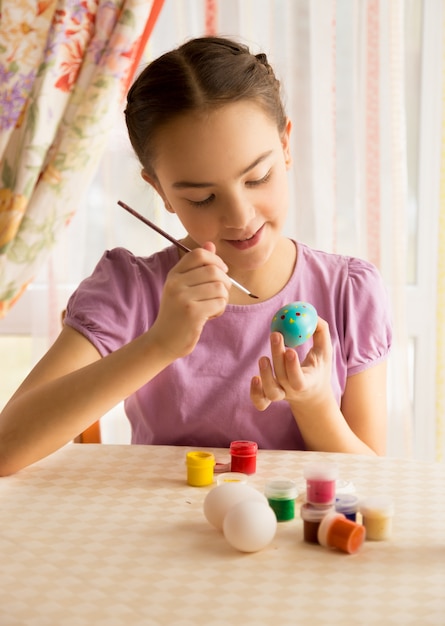 Closeup portret van schattig meisje met penseel paaseieren schilderen