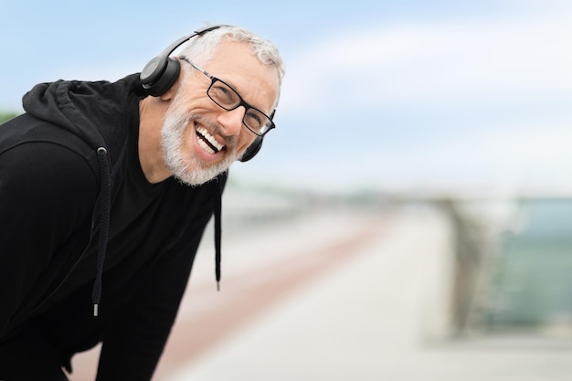 Closeup of positive elderly sportsman having break while jogging